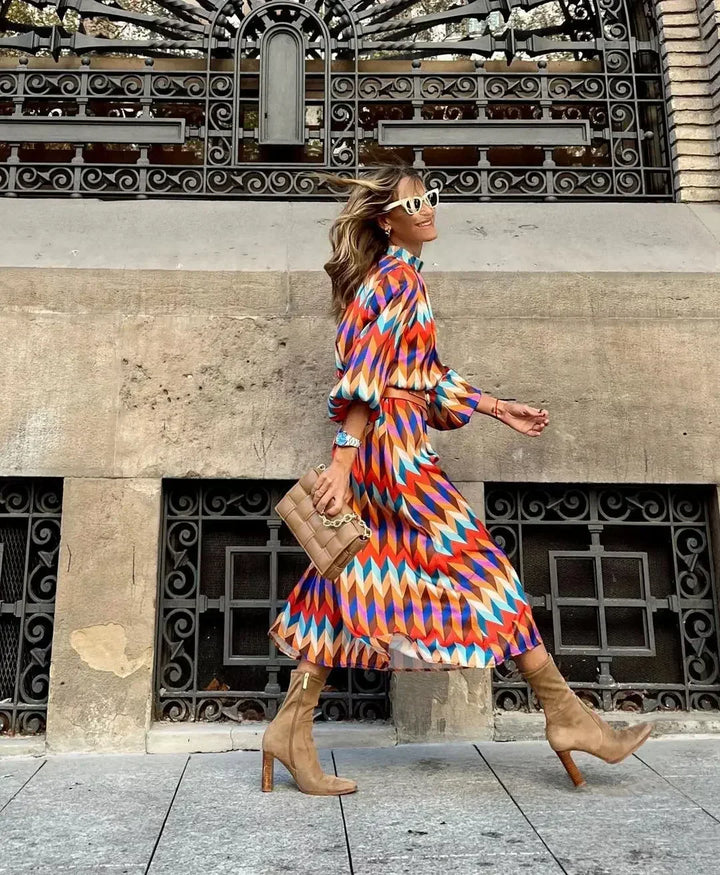 Woman in the Caroline geometric print maxi dress with a high neckline and puff sleeves, walking through a city street.