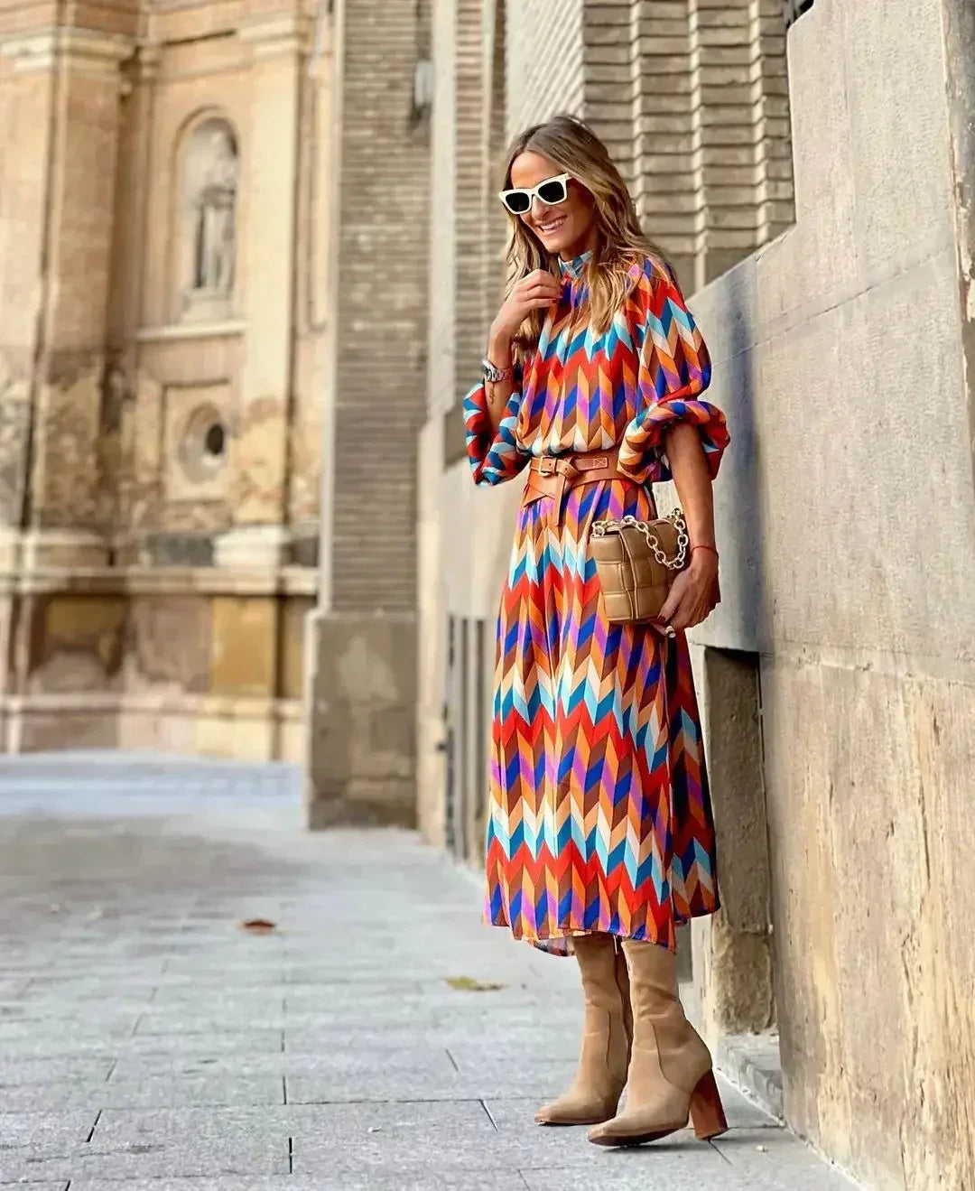 Woman in the Caroline geometric print maxi dress with a high neckline and puff sleeves, walking through a city street.