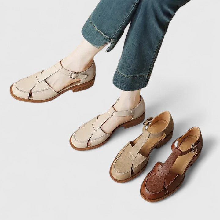 Woman wearing beige strapped Mary Jane sandals on a sunny terrace.