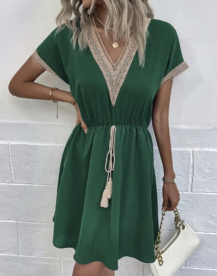 A woman wearing a relaxed boho dress with fringe accents and delicate openwork detailing.