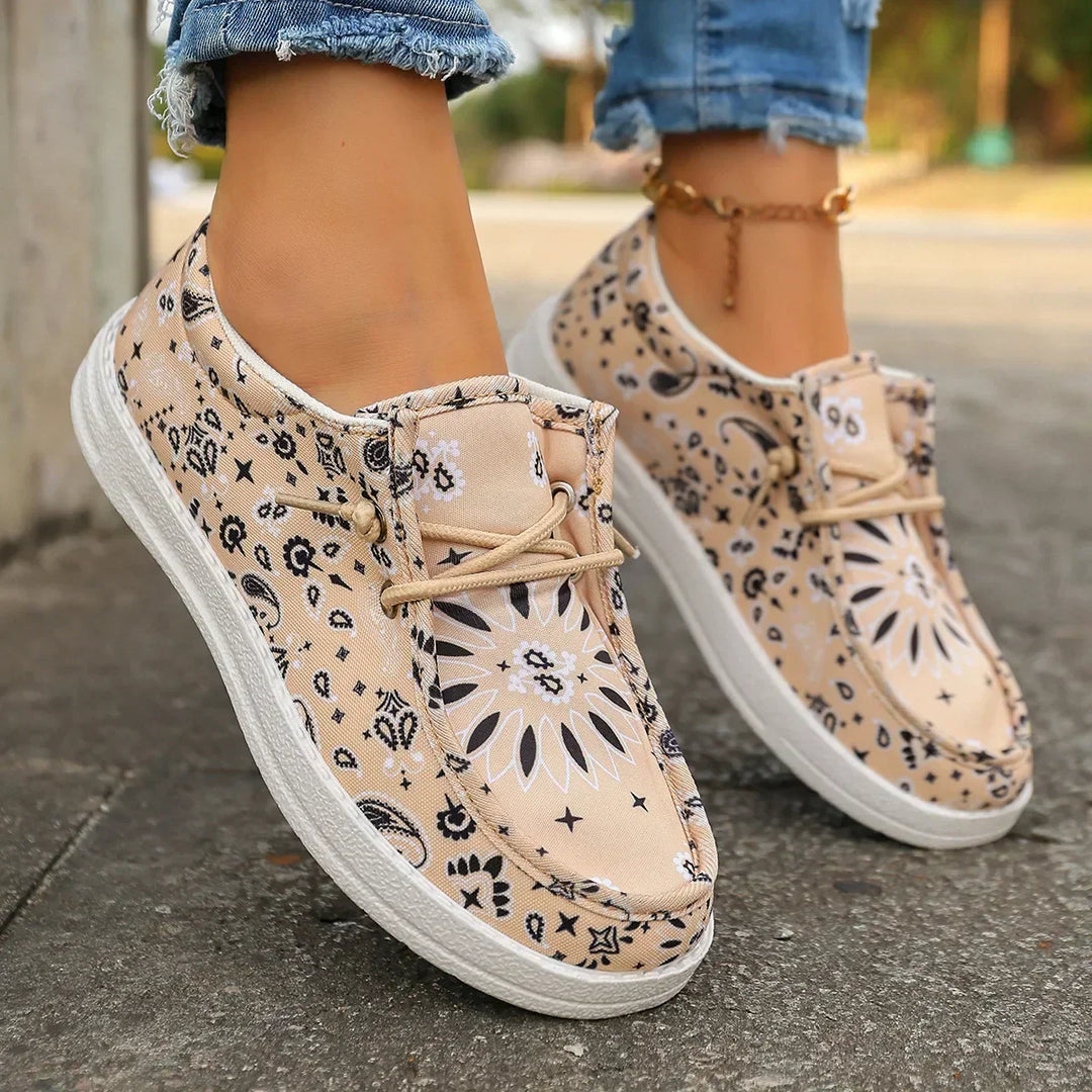 A woman wearing soft cream boho-print lace-up comfort shoes on a bright summer day.