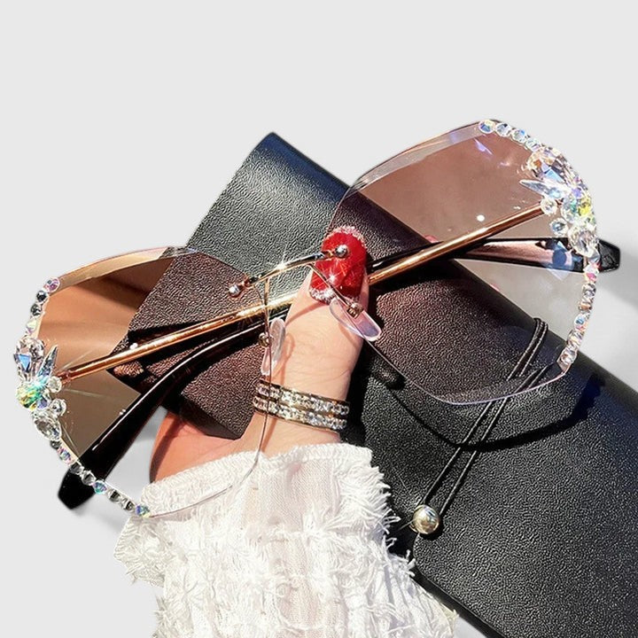 A woman at a special occasion wearing rimless sunglasses with sparkling diamanté accents, catching the light.