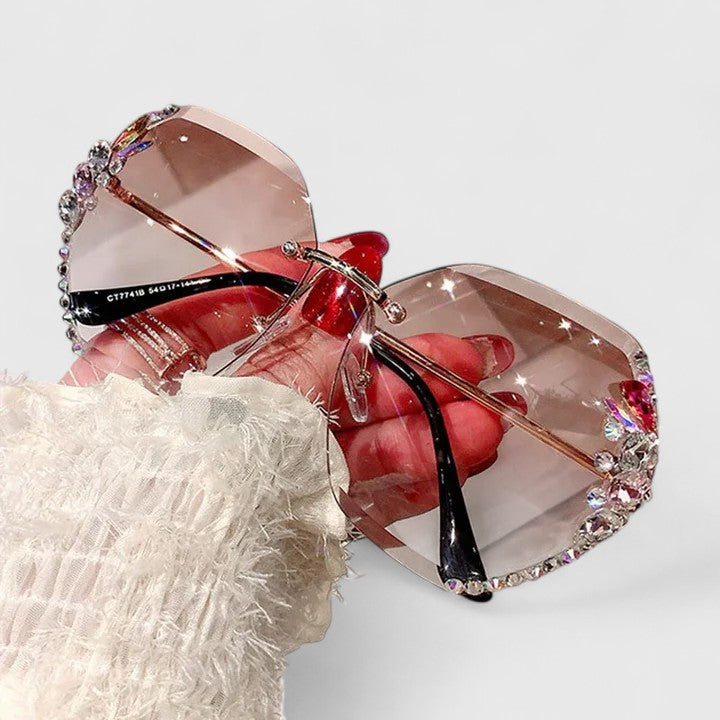 A woman at a special occasion wearing rimless sunglasses with sparkling diamanté accents, catching the light.