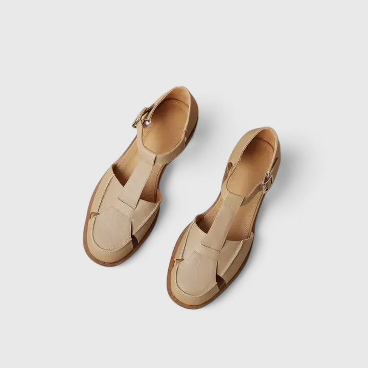 Woman wearing beige strapped Mary Jane sandals on a sunny terrace.