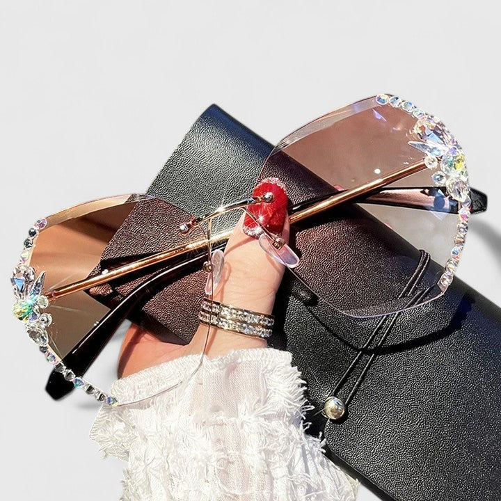 A woman at a special occasion wearing rimless sunglasses with sparkling diamanté accents, catching the light.