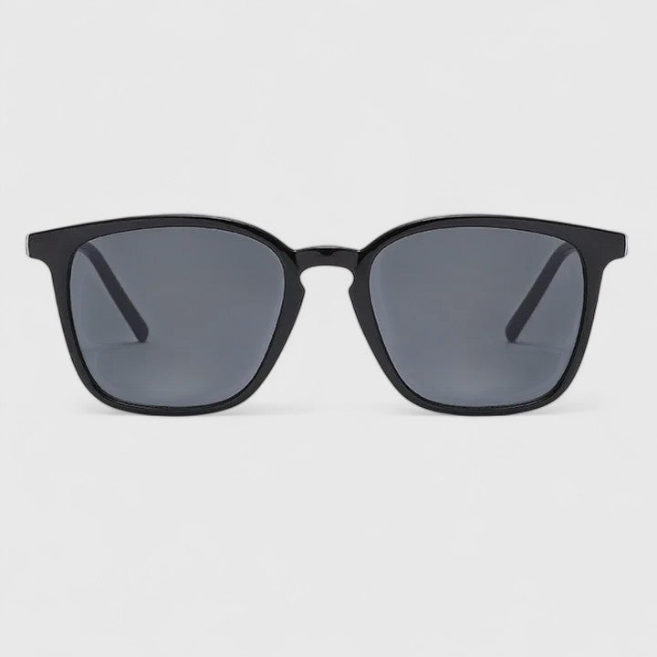A woman on a sunny day wearing rectangular retro sunglasses, relaxed and stylish.
