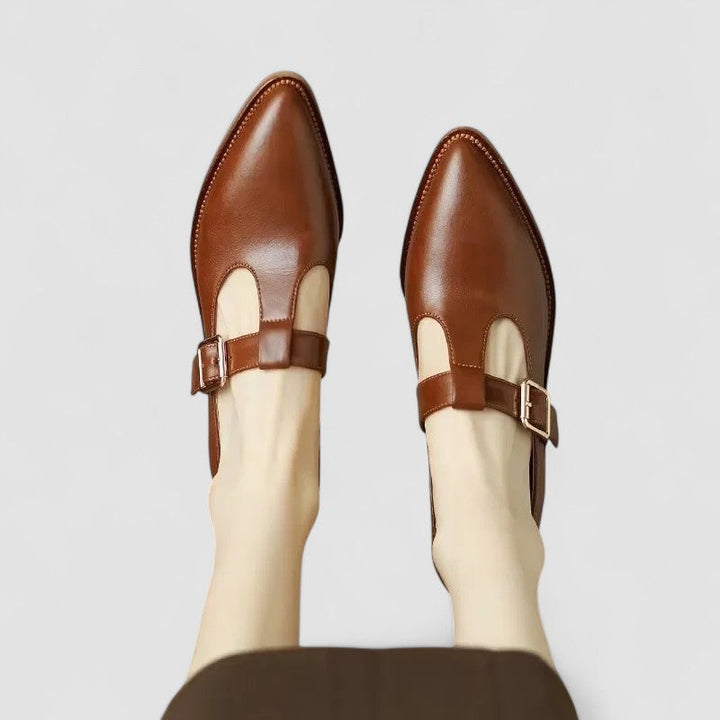 A woman in beige Mary Jane shoes with a mid block heel, poised at a daytime wedding.