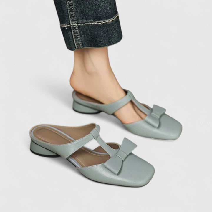 Soft green bow-detail mules with a slim T-strap, open back and a low heel.