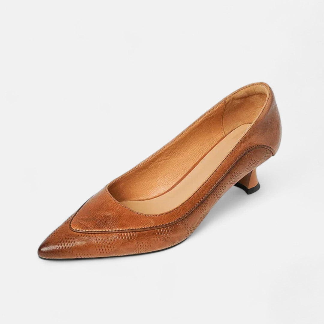 A woman wearing black pointed kitten-heel pumps with a subtle embossed finish.