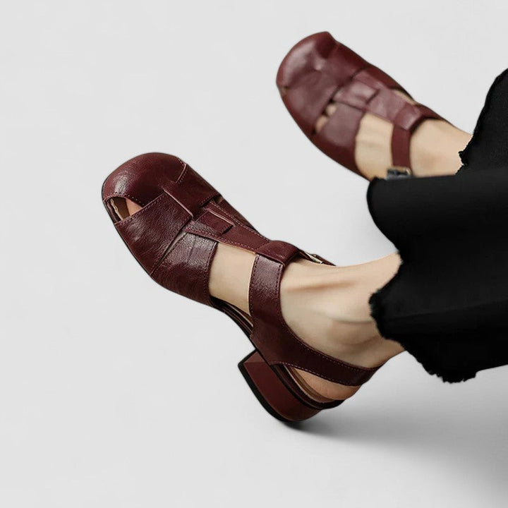 A woman in burgundy closed-toe woven sandals with a low block heel, comfortable browsing a market.