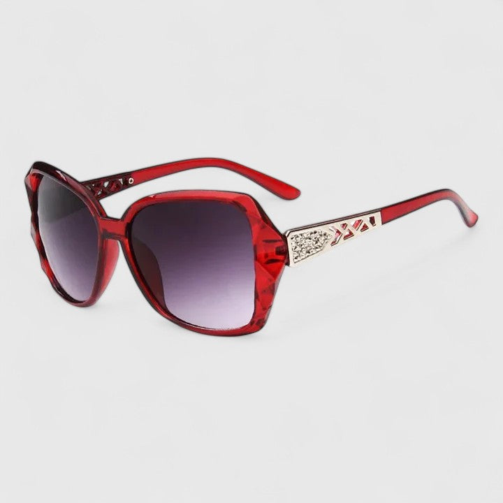 A woman on a sunny city street wearing chic square-frame sunglasses, smiling confidently.