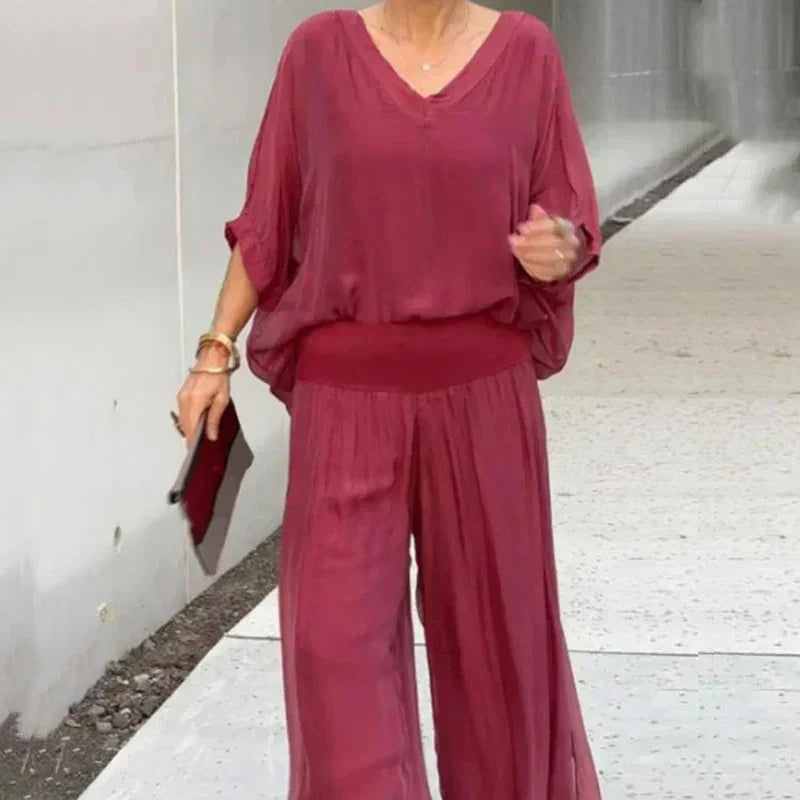 A woman wearing a flowing lounge two-piece set with a V-neck top and wide-leg pants.
