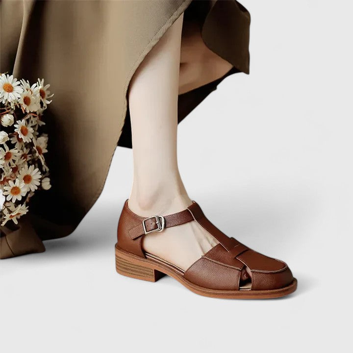 A woman wearing brown Mary Jane sandals with a T-strap and buckle, paired with a summer dress.