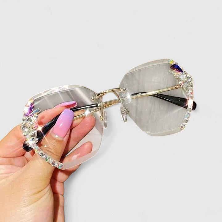 A woman at a special occasion wearing rimless sunglasses with sparkling diamanté accents, catching the light.