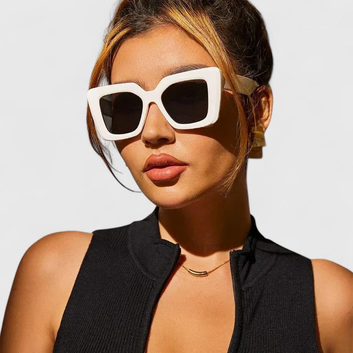 A woman at golden hour wearing bold geometric sunglasses, poised and glamorous in the sun.