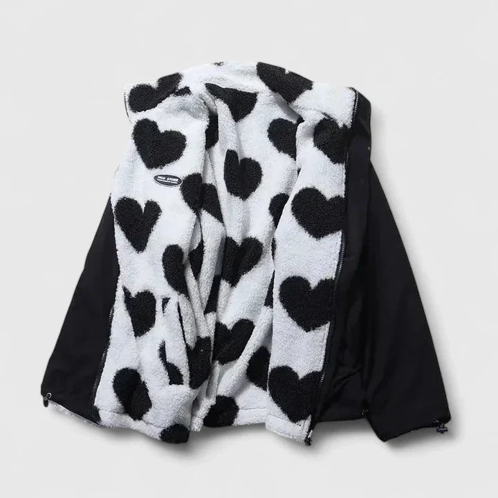 A woman wearing a plush white zip jacket with a bold black heart print and a high collar.