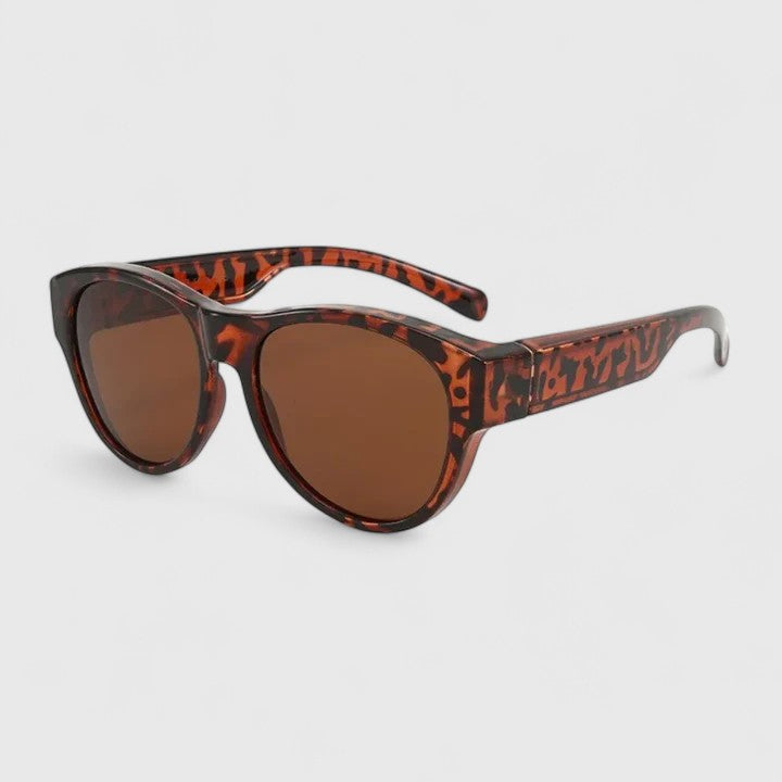 A woman wearing fit-over polarised sunglasses over her own glasses, comfortable in the sunshine.