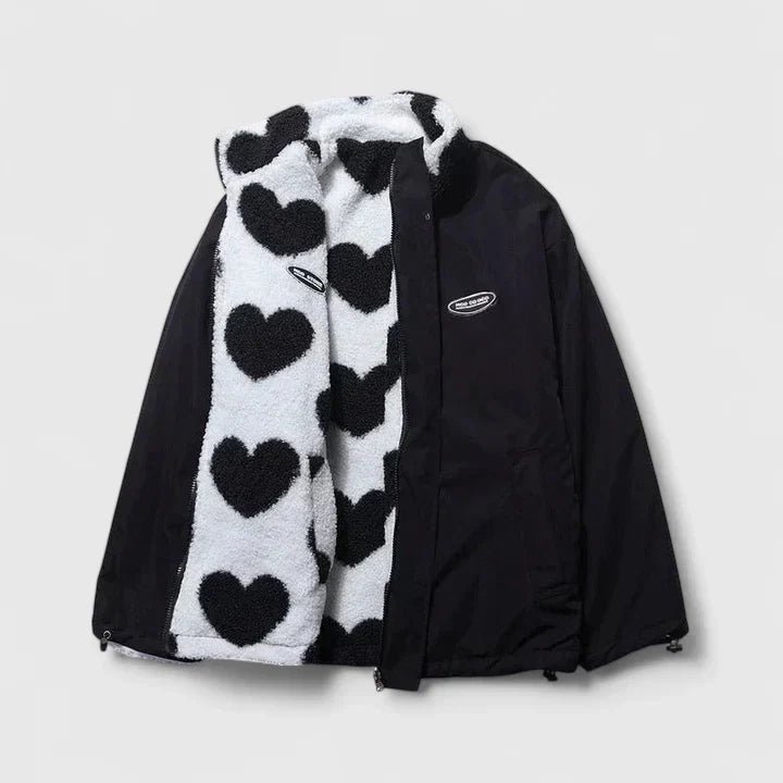 A woman wearing a plush white zip jacket with a bold black heart print and a high collar.