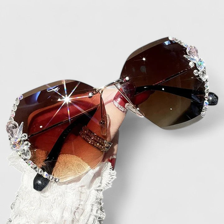 A woman at a special occasion wearing rimless sunglasses with sparkling diamanté accents, catching the light.