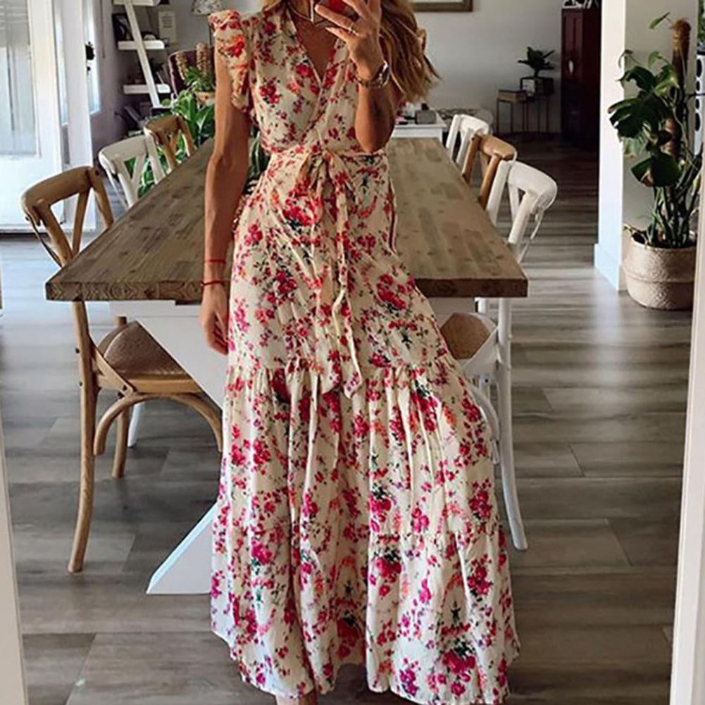 Woman in a flowing floral maxi dress with a tied waist at a summer garden gathering.