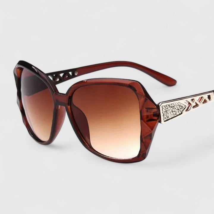 A woman on a sunny city street wearing chic square-frame sunglasses, smiling confidently.