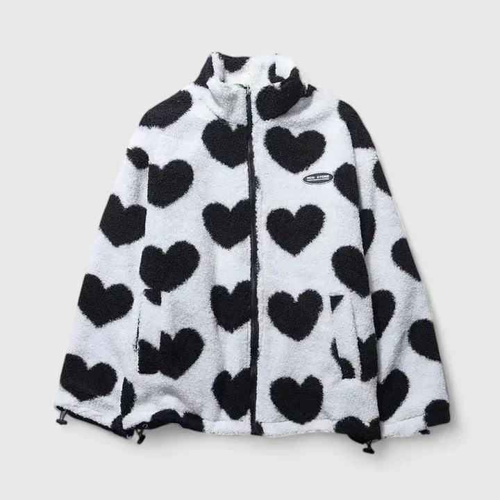A woman wearing a plush white zip jacket with a bold black heart print and a high collar.