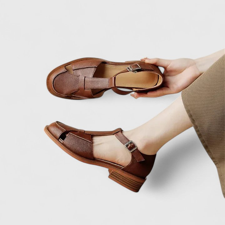Woman wearing beige strapped Mary Jane sandals on a sunny terrace.