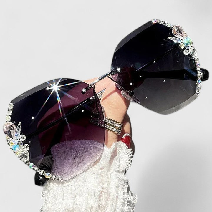 A woman at a special occasion wearing rimless sunglasses with sparkling diamanté accents, catching the light.