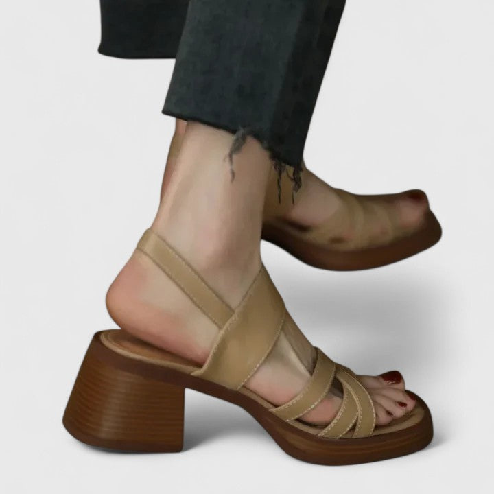 A woman wearing elegant cross-strap sandals with a summer dress, looking graceful and comfortable.