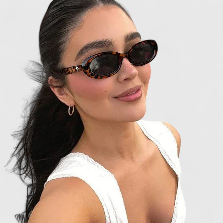 A woman in the city wearing chic oval sunglasses, confident and stylish in the sun.