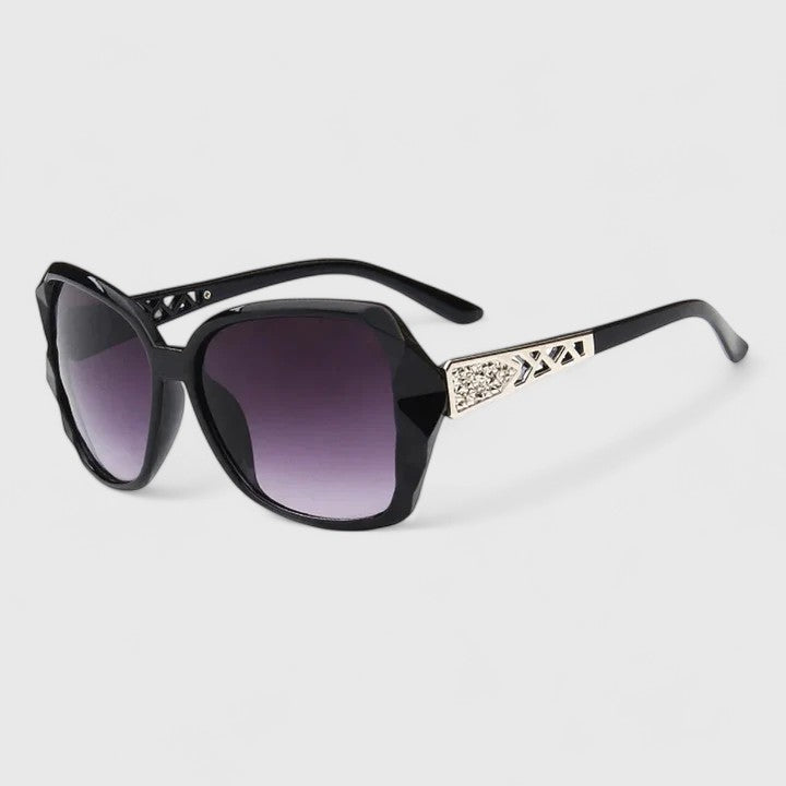 A woman on a sunny city street wearing chic square-frame sunglasses, smiling confidently.