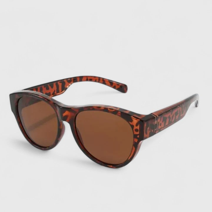 A woman wearing fit-over polarised sunglasses over her own glasses, comfortable in the sunshine.