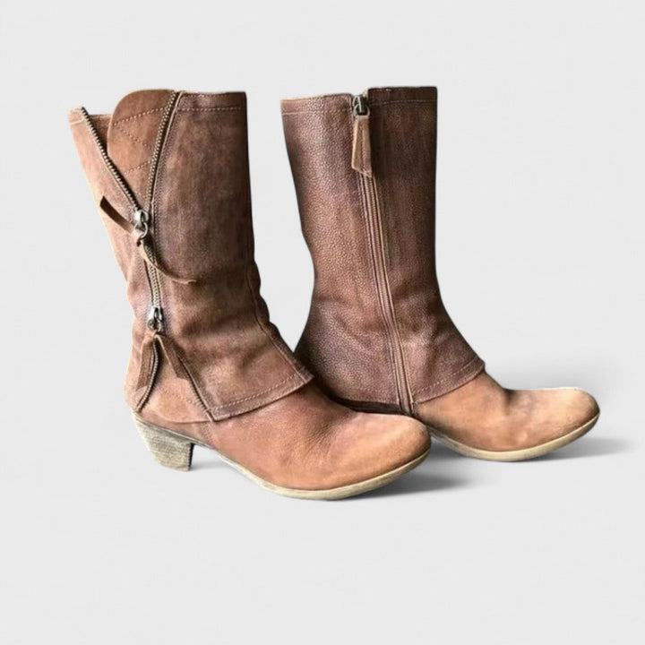 A woman in slim jeans wearing brown mid-calf boots with buckle detailing and a squared heel.