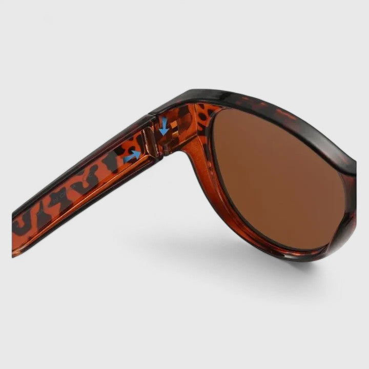 A woman wearing fit-over polarised sunglasses over her own glasses, comfortable in the sunshine.