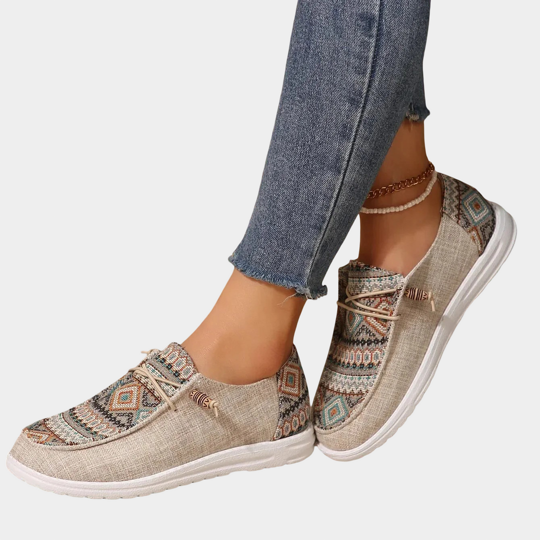 A woman wearing khaki boho-patterned lightweight sneakers on a walk in town.