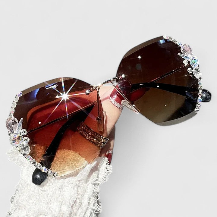 A woman at a special occasion wearing rimless sunglasses with sparkling diamanté accents, catching the light.