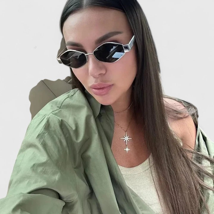 A woman wearing retro hexagonal metal-frame sunglasses on a sunny street.