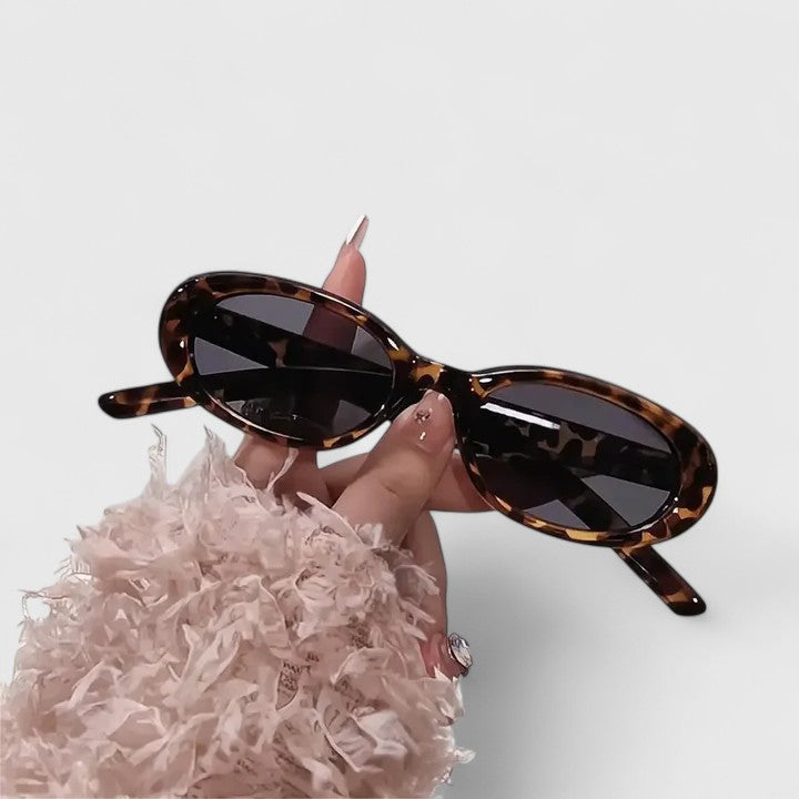 A woman in the city wearing chic oval sunglasses, confident and stylish in the sun.