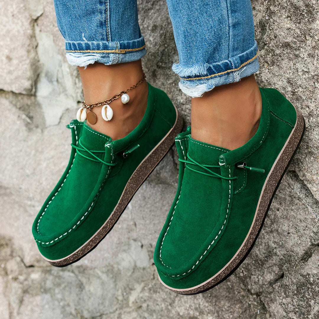 A woman wearing bright green lace-up platform comfort shoes on a walk through the garden.