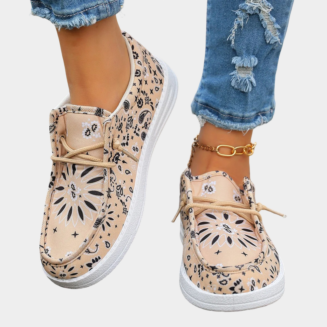 A woman wearing soft cream boho-print lace-up comfort shoes on a bright summer day.