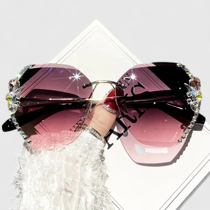 A woman at a special occasion wearing rimless sunglasses with sparkling diamanté accents, catching the light.