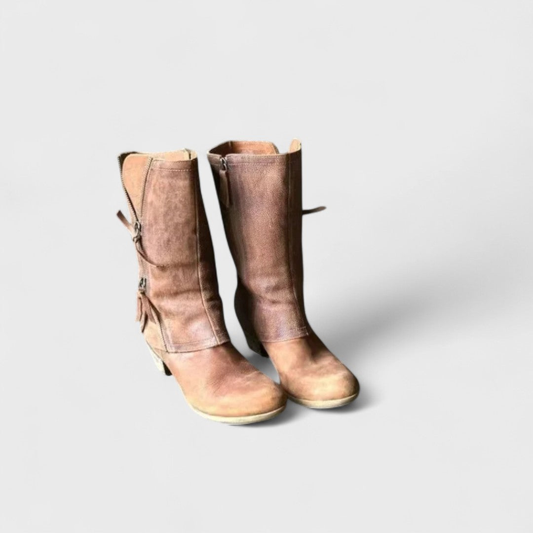 A woman in slim jeans wearing brown mid-calf boots with buckle detailing and a squared heel.