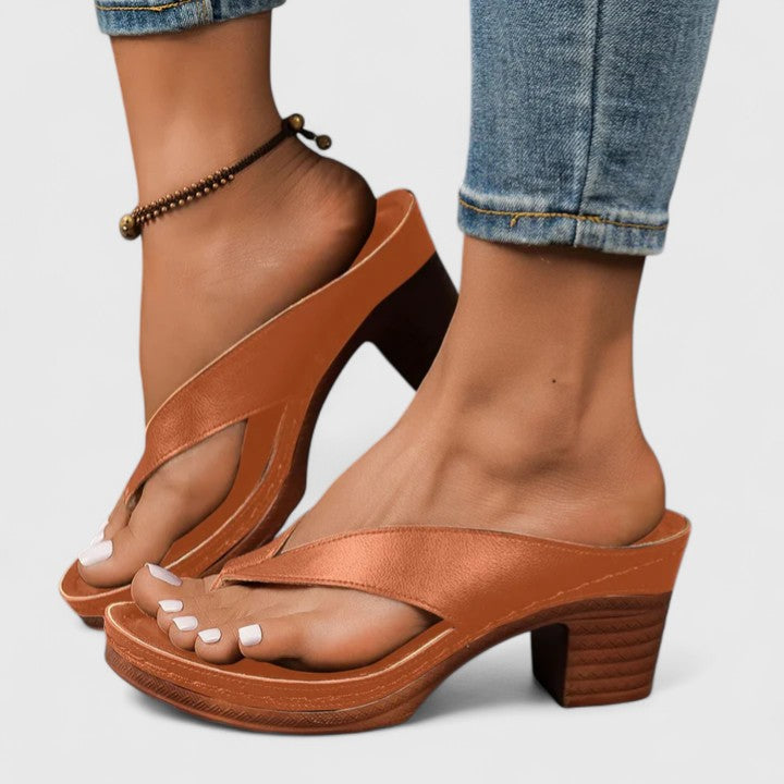 A woman in black open toe-post sandals with a chunky squared heel, walking easily through an evening event.