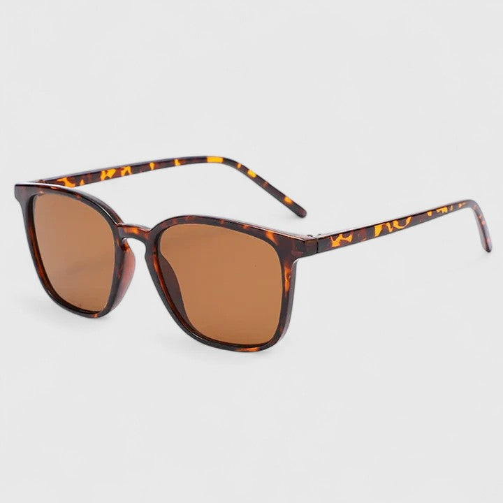 A woman on a sunny day wearing rectangular retro sunglasses, relaxed and stylish.