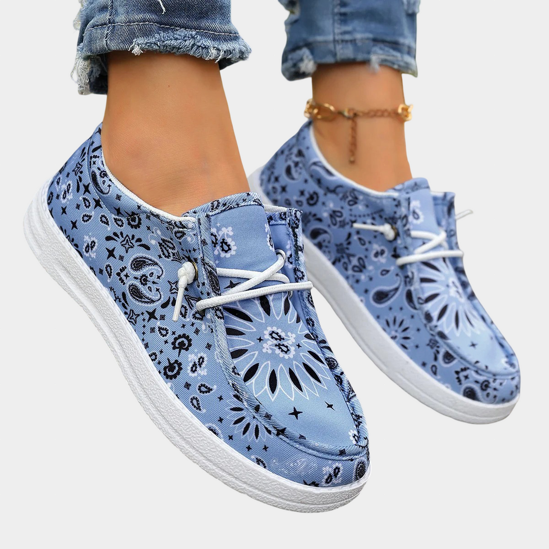 A woman wearing blue boho-print lace-up comfort shoes on a coastal walk.