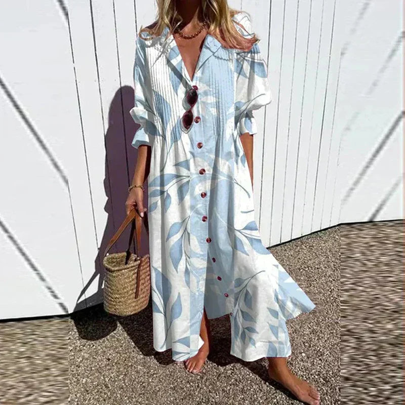 Woman wearing the Gail™ leaf print maxi dress with a button front, walking along the coast in a light breeze.