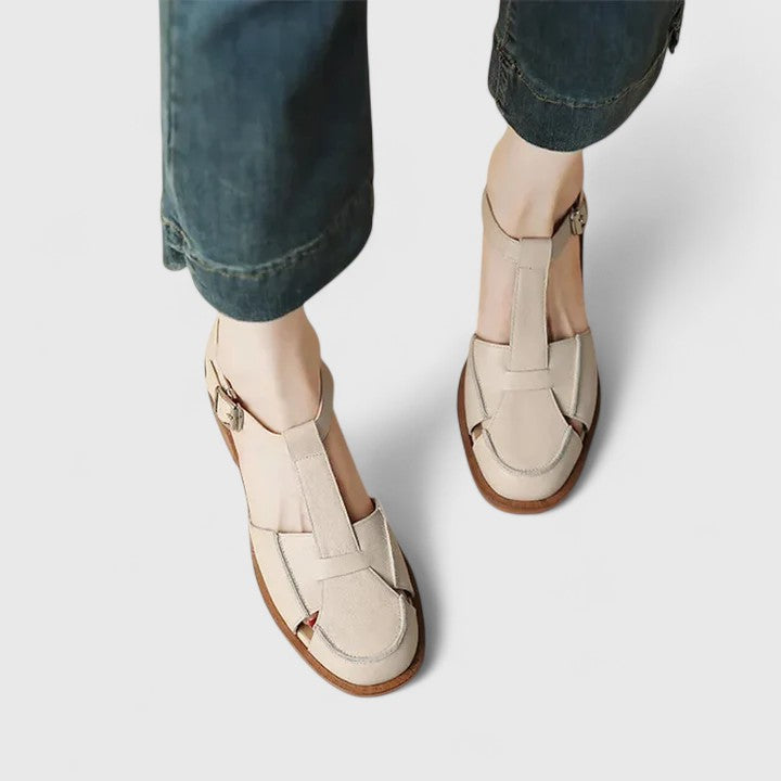 Woman wearing beige strapped Mary Jane sandals on a sunny terrace.