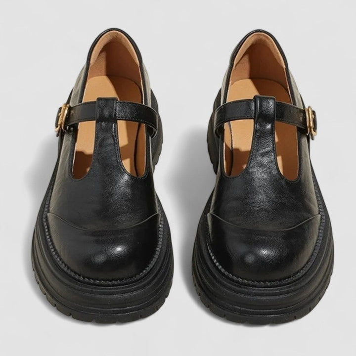 Woman wearing brown Mary Stacey comfort shoes with a T-strap, standing on a city footpath.