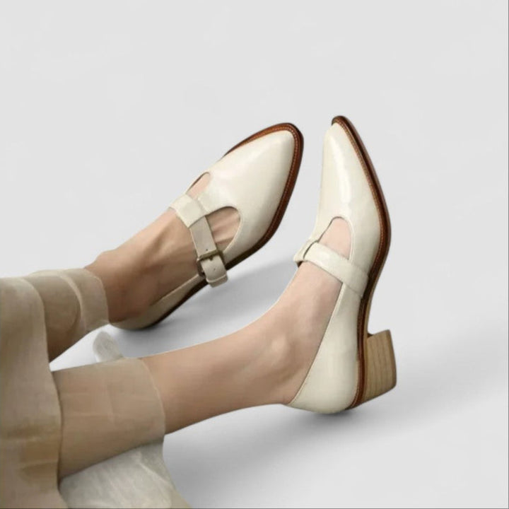 A woman in beige Mary Jane shoes with a mid block heel, poised at a daytime wedding.
