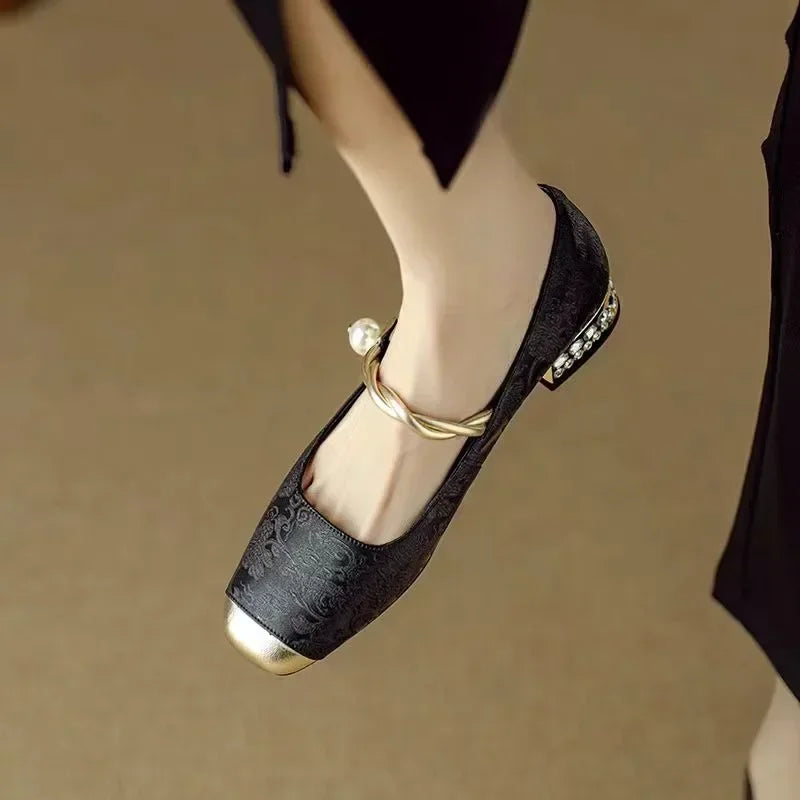 A woman wearing green low-heel Mary Janes with a twisted gold strap, gilded cap toe and a crystal-set heel